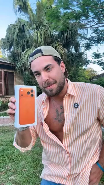 Cliente mostrando um iPhone laranja comprado na loja